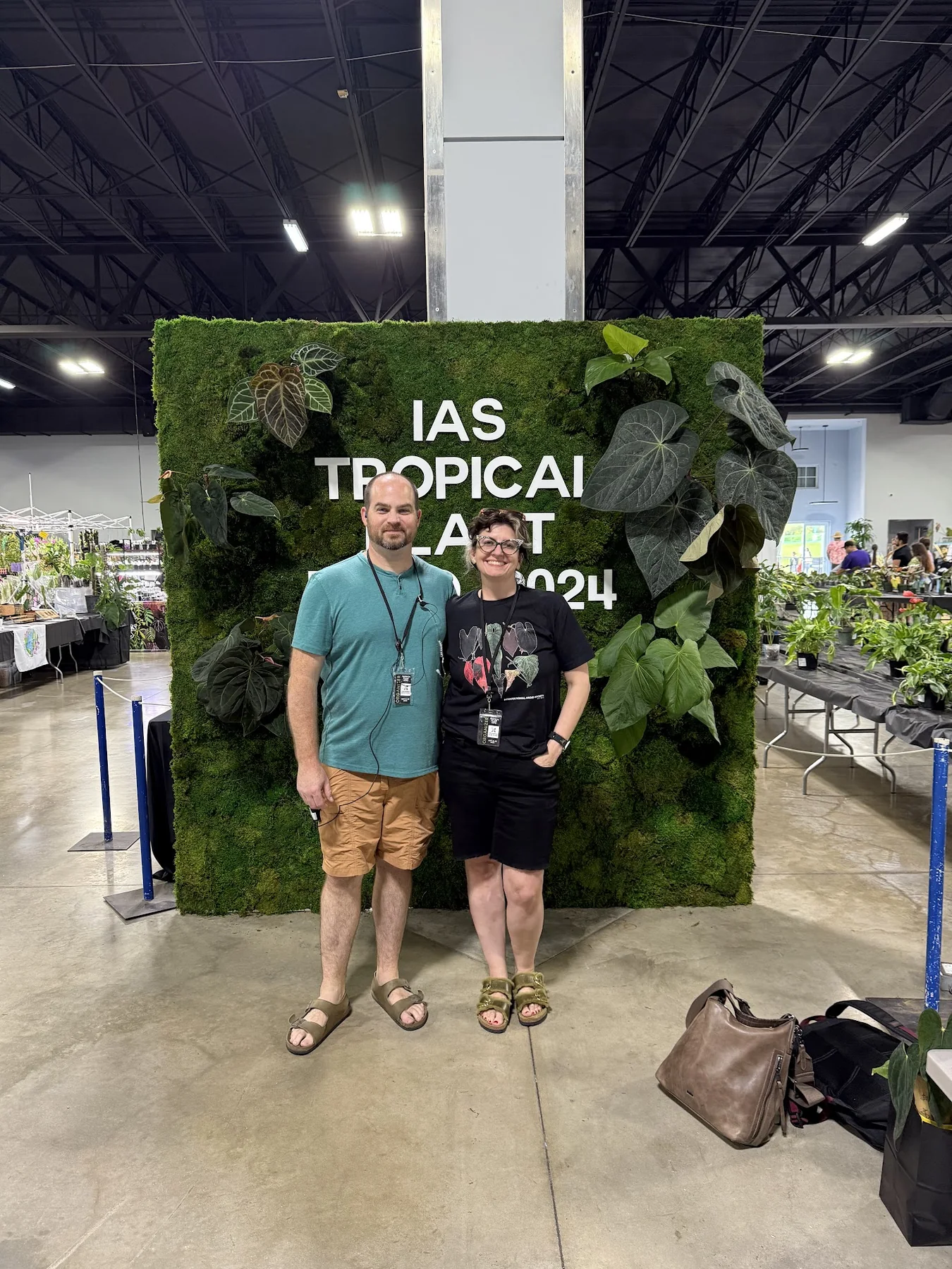Justin and Sam standing in front of the 2024 Tropical Plant Expo plant wall