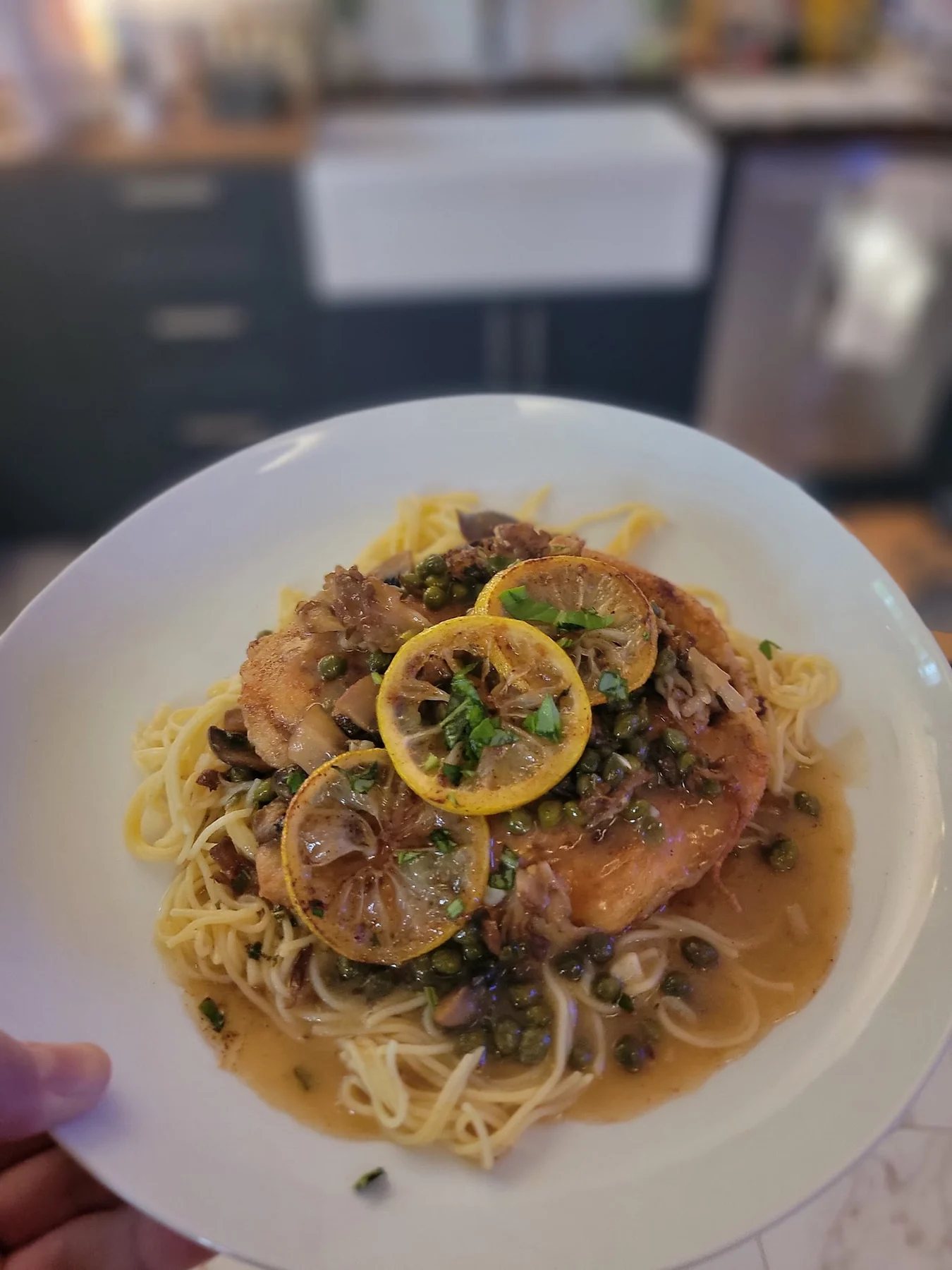Chicken piccata with browned lemon slices, capers, mushrooms, and pasta